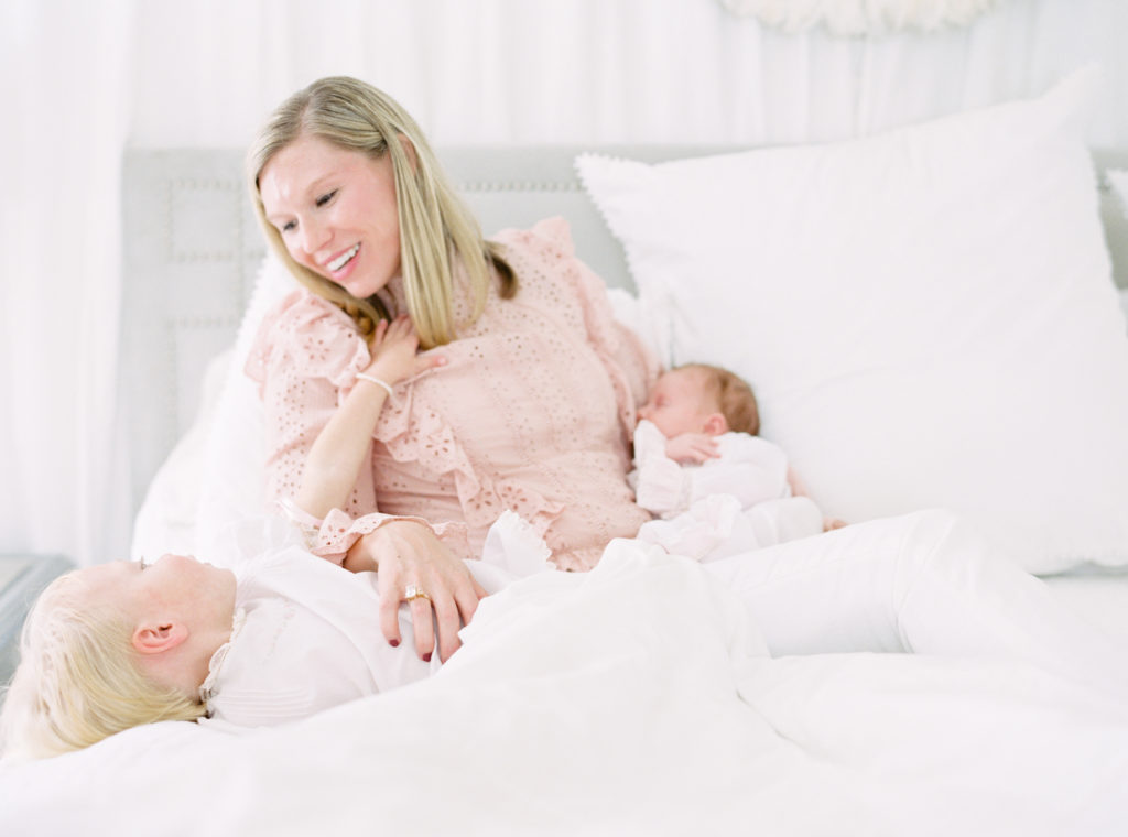 Smiling mom on her bed with her child and newborn baby