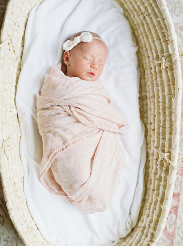 Sleeping newborn in a light pink swaddle.