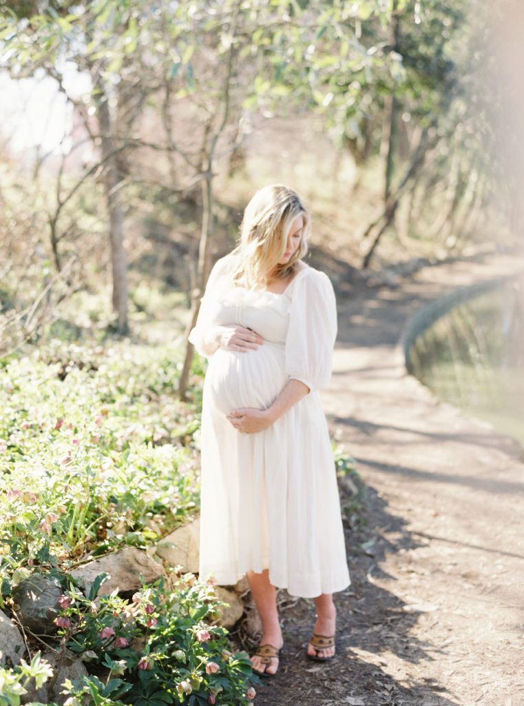 Pregnant woman holding belly during outdoor maternity session