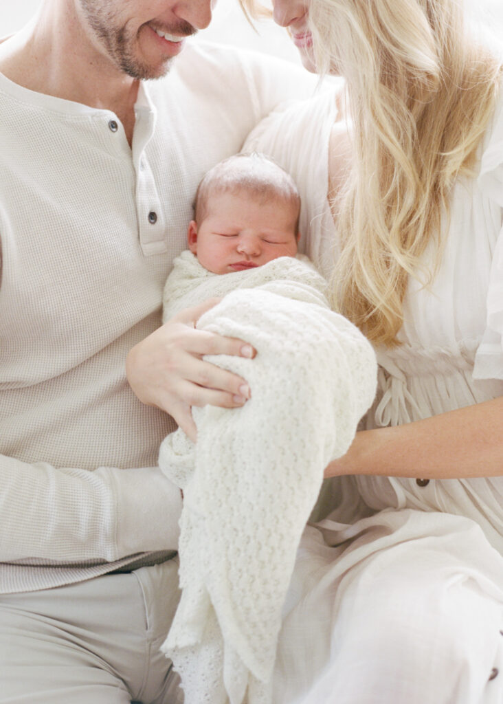 New parents holding baby during best time for newborn photography session