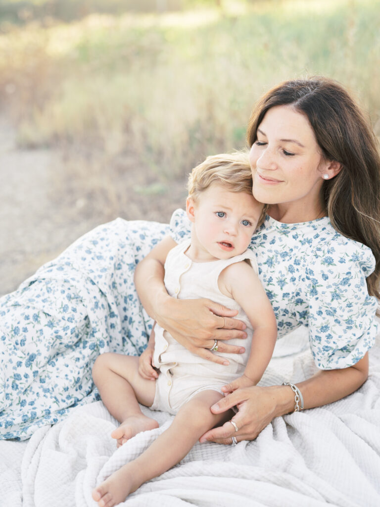 Toddler sitting on blanket with mom during autumn family session