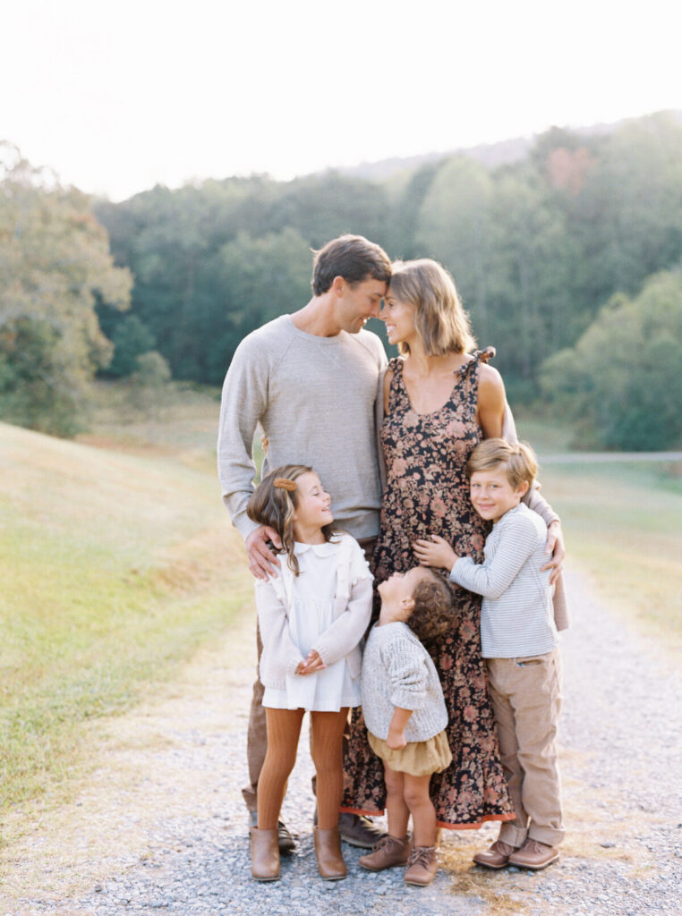 Family of five walking through a Birmingham, AL park in coordinated neutral outfits for timeless fall portraits