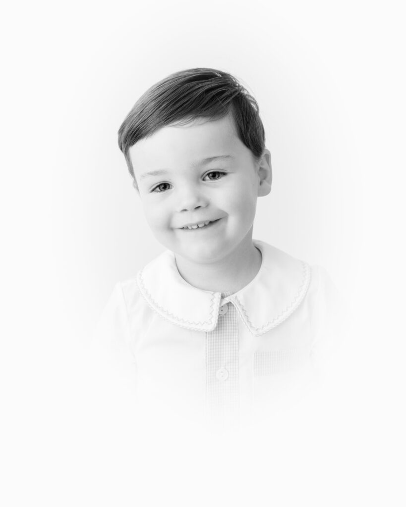 Close-up heirloom portrait showing a child’s gentle smile and bright eyes captured in a classic vignette style