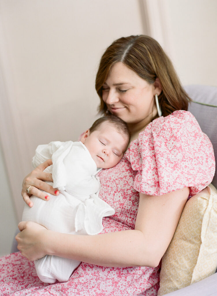 Mother holding her newborn baby in soft natural light, photographed by a luxury Birmingham newborn photographer.