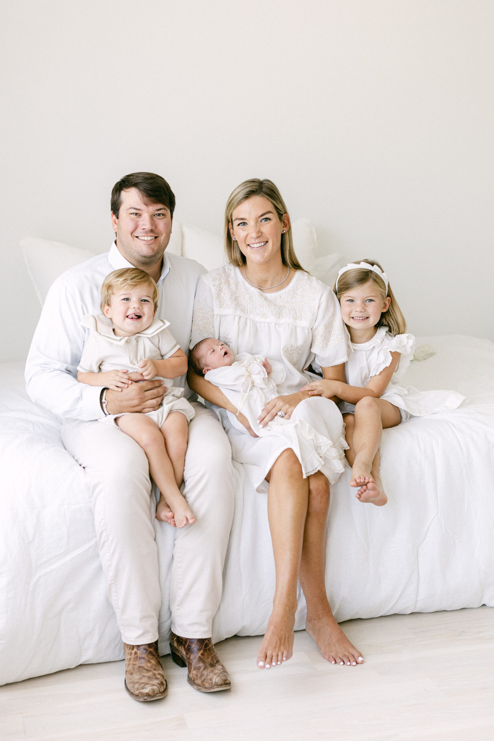 A heartwarming studio portrait of siblings or a family with their newborn, captured in a timeless and classic arrangement.