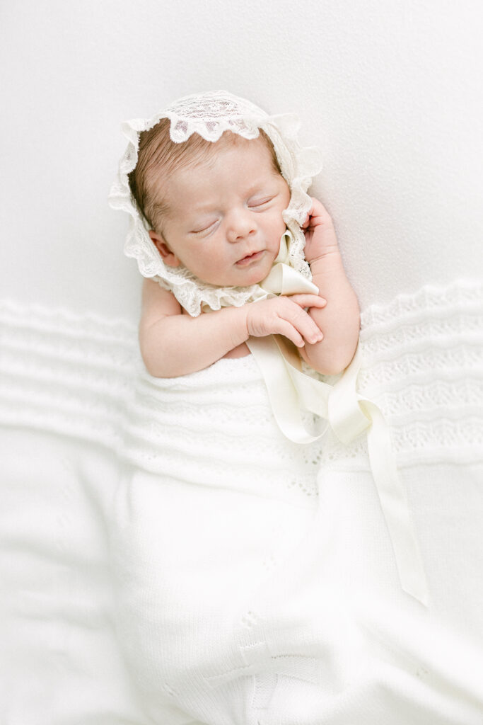 A minimalist studio setup with a newborn lying on a neutral backdrop, soft lighting highlighting delicate features.