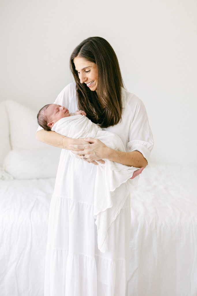 Parent holding newborn in a studio, shot framed to highlight gentle connection and warm light.