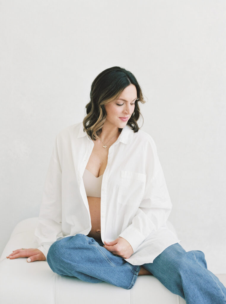 Pregnant mother wearing an oversized white button-down shirt and jeans for a modern maternity photography look.