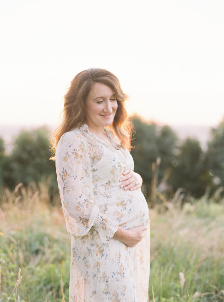 Expecting mother wearing a flowing dress during an outdoor maternity photography session at sunset in Birmingham, Alabama.
