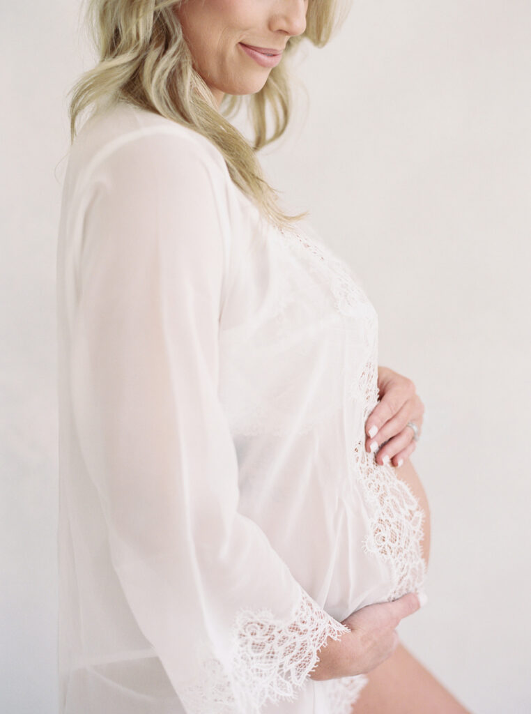 Close-up maternity portrait highlighting a pregnant mother’s baby bump with soft, timeless styling.